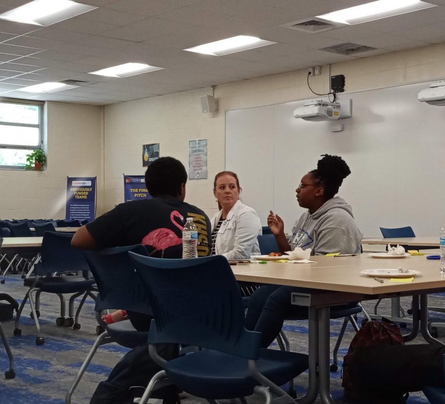 N’Kosi-Sanai Poole (left), Principal Melissa George (center), and Jada Jones (right) talk about school spirit and Monday Morning Meetings in the EBA space on October 3 during lunch. 