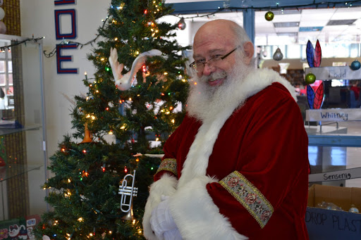 Mr. David Springstead, dressed as Father Christmas, stands in front of the Christmas tree set up in the foyer. It previously displayed the bulbs for “Be a Santa to a Senior,” which was sponsored by Kempsville’s security team. 